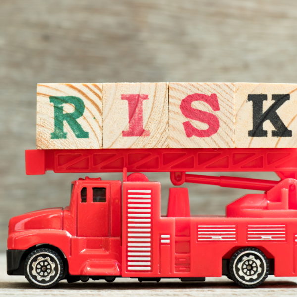 Red fire truck with ladder hold block word risk on wood background